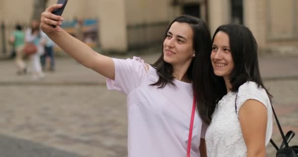 Brunettes caucasiennes dans la ville prendre selfie. En plein air. Les sœurs sourient et ont l'air heureuses — Video