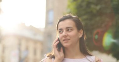 Güzel kadın üzerinde cep telefonu açık havada söz. Bir kız arkadaşı ile sohbet ediyor.