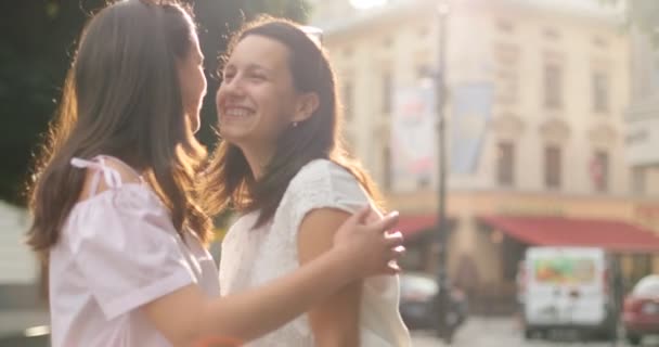 Atractivas morenas abrazándose. Las chicas están felices de verse. Al aire libre . — Vídeos de Stock