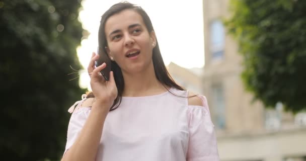 Hermosa mujer hablando por celular al aire libre. Una chica está teniendo una conversación con su amiga. Al aire libre . — Vídeo de stock