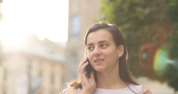 Hermosa mujer hablando por celular al aire libre. Una chica está teniendo una conversación con su amigo . — Vídeos de Stock