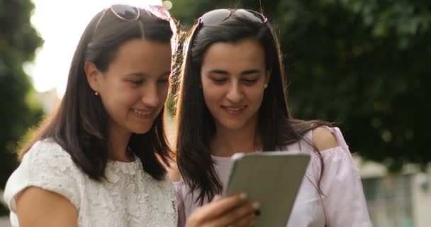 Близькі друзі перевіряють планшетний пристрій на відкритому повітрі . — стокове відео