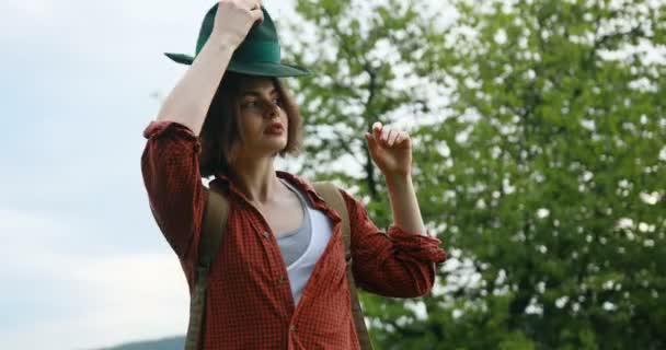 Τουριστική νεαρή γυναίκα φοράει καπέλο περπάτημα στο βουνό. — Αρχείο Βίντεο
