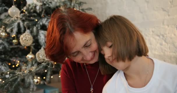 Little girl hugging her grandmother. Family exchanging gifts at Christmas. They looking at camera. Christmas holiday and New Year. — Stock Video