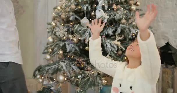 Hermana y traidor siendo excitado con confeti colorido chispeante cayendo todo alrededor, fondo del árbol de Navidad. Vacaciones de Navidad y Año Nuevo . — Vídeos de Stock