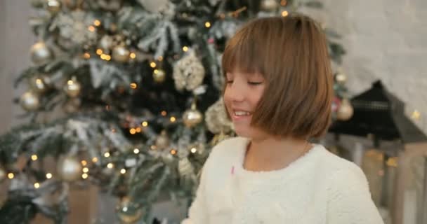 Malé radostné holčičky byly nadšeni s šumivé barevné konfety pádu všude kolem, vánoční stromeček pozadí. Vánoční svátky a nový rok.