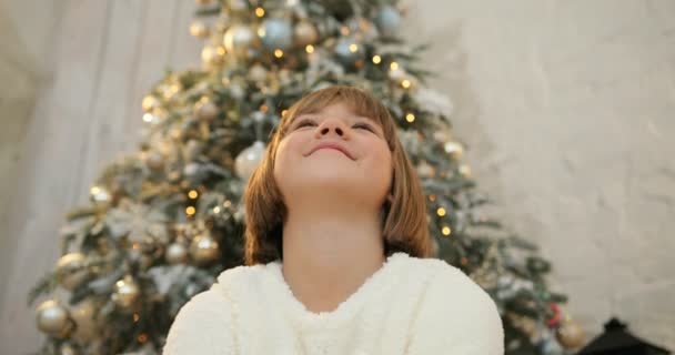 Lycklig liten flicka att vara upphetsad med glittrande färgglada konfetti faller runt omkring, julgran bakgrund. Jullov och nyår. — Stockvideo