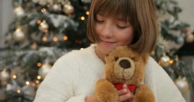 Yakın çekim shot bir sevimli küçük kız onun oyuncak ayı Noel hediyesi sarılma. Xmas parti kutlama, çocukluk. Noel ağacı backgroung. Noel ve yeni yıl.