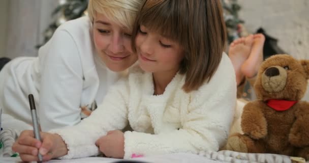 X-mas 党庆祝, 童年。母亲和女儿的画像躺在装饰圣诞树附近, 写圣诞信给圣诞老人 — 图库视频影像