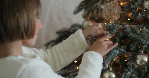 Ung flicka att sätta prydnad på julgran — Stockvideo