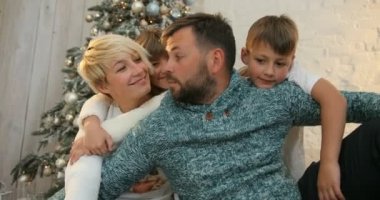 Gülümseyen aile birlikte Noel günü kutluyor. Onlar birbirlerini Noel ağacı arka plan sarılma. Tatil ve yeni yıl.