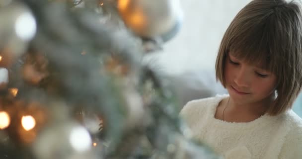 Menina jovem colocando ornamento de brinquedo na árvore de Natal . — Vídeo de Stock
