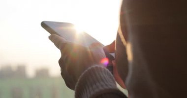 El tutma akıllı telefon. Pencere duran cep telefonu kullanan kız. Arkadan Görünüm vurdu.