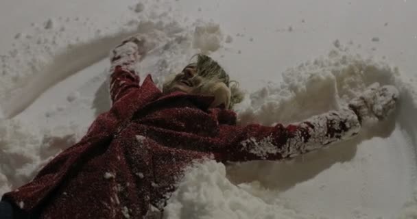 Jeune femme faisant des anges de la neige dans la ville la nuit — Video