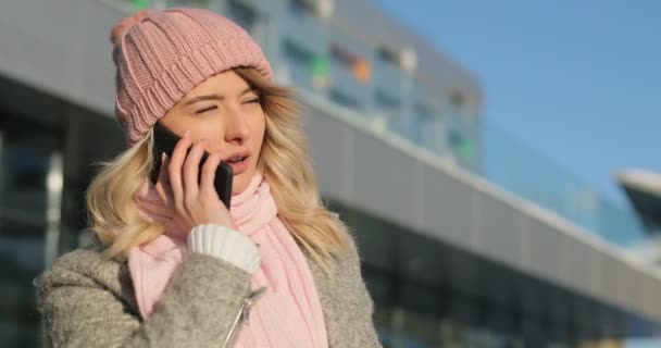 快乐的女孩在电话里聊天, 冬城街, 雪圣诞节。穿着冬季大衣和粉红色围巾的智能手机上的女人说话 — 图库视频影像