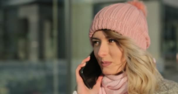 Портрет очаровательной девушки, отвечающей на звонки, разговаривающей по смартфону, идущей по улице. Наслаждаясь снегопадом, выражая позитивность, радостное веселое настроение, новогоднее настроение — стоковое видео