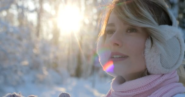 Ritratto di giovane ragazza che indossa un pullover bianco invernale e una sciarpa rosa cercando di riscaldarsi nel parco invernale. Bel tempo, il sole splende . — Video Stock