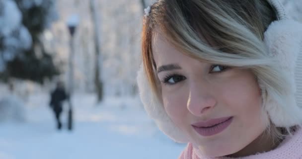 Primer plano retrato de hermosa chica feliz en el parque de invierno helada. Al aire libre. Copos de nieve voladores, día soleado. retroiluminado. Sonriendo a la cámara, alegre humor alegre, emociones — Vídeos de Stock