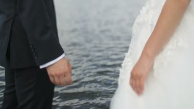 Yeni evli evlilik çift deniz arka plan üzerinde elele. Damat gelinin elinden alır.