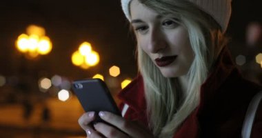 Yakın çekim açık geceleri sokak cep telefonu kullanan güzel genç kadın portresi. Kış, neşeli Noel arka plan üzerinde Fuarı.