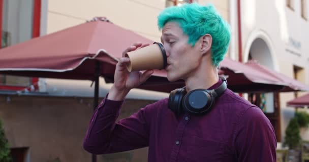 Πορτρέτο του νεαρού καυκάσιου όμορφου χίπστερ με πράσινα μαλλιά που πίνει καφέ στο δρόμο της πόλης και μετά χαμογελάει στην κάμερα. Κλείσε.. — Αρχείο Βίντεο