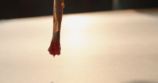 Close up of the white blank sheet of paper and a brush with red paint on it painting a waving line on it. — ストック動画