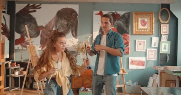 Caucasian young couple of painters dancing and having fun in the cozy artistic studio while having a break from work. — Stock Video