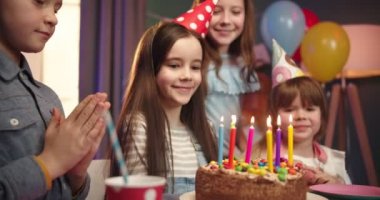 Doğum günü pastasını kapat. Masanın üzerinde mumlar, mutlu doğum günü kızı ve arka planda neşeli arkadaşları olsun..