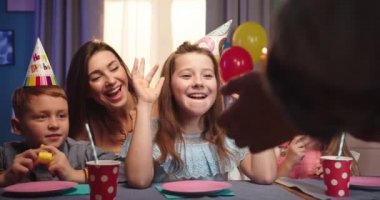 Kafkas güzelinin portre fotoğrafı. Arkadaşlarıyla masada oturup mum üflerken çok mutlu olan küçük bir kız..