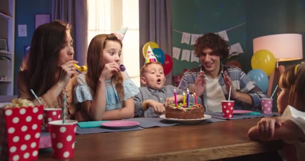 Zdjęcie portretowe wesołej białej rodziny świętującej urodziny małego syna, podczas gdy chłopiec dmucha świeczki na tort. — Wideo stockowe