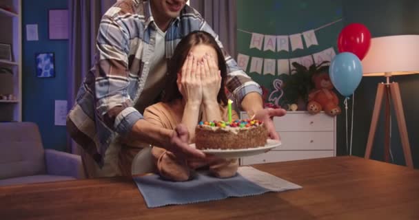 白人若いです魅力的な妻座っていますテーブルと彼女の夫もたらす誕生日ケーキとともにキャンドルそれ彼女の吹いて. — ストック動画