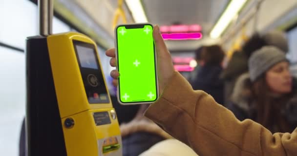 Lviv, Ukraine - 25.12.2019: Close up of female hand holding vertical smartphone with chroma key screen and tracking motion at the tram or bus near the device for paying. — Stockvideo