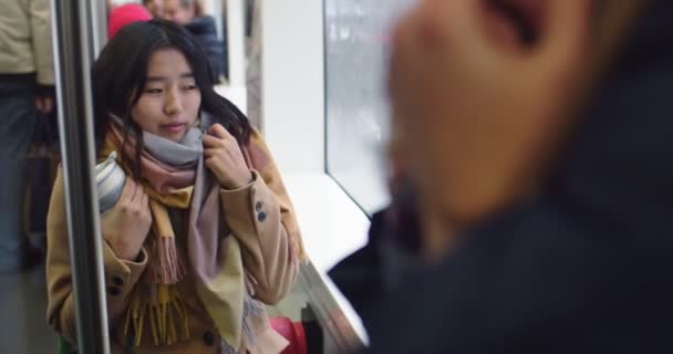 Aziatisch jong mooi en stijlvol meisje zitten in de tram of bus met een kopje hete koffie of thee te gaan en het gevoel koud. — Stockvideo