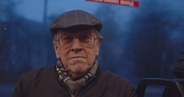 Ritratto dell'anziano pensionato caucasico di bell'aspetto che guarda nella macchina fotografica con un sorriso mentre è seduto sul tram o sull'autobus la sera. Da vicino. . — Video Stock