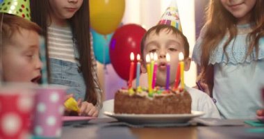 Mutlu arkadaşları bakıp gülümserken doğum günü kutusundaki beyaz çocuğun pastaya mum üflemesini kapat..
