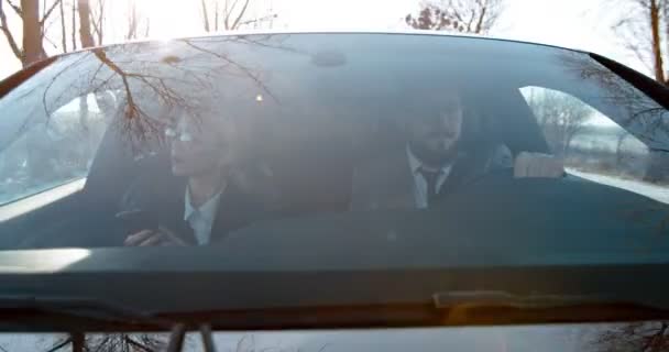 Кавказький бізнесмен за кермом автомобіля і його красива дружина або колега по роботі сидять біля нього. Подивіться на вітрове скло. — стокове відео