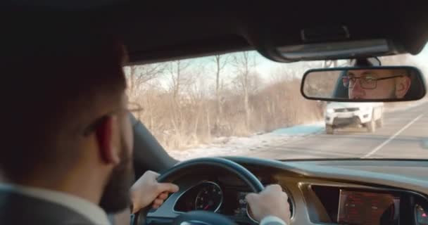 Im Hintergrund der kaukasische Geschäftsmann mit Brille, der an dem schönen Herbstsonnigkeitstag ein schönes Auto außerhalb der Stadt fährt. zurück. — Stockvideo