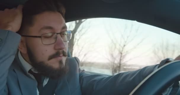 Close up of the Caucasian anxious man driver in the tie and glasses driving a car and fixing his hair with a hand. — 비디오