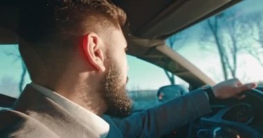 Kafkasyalı sakallı, takım elbiseli, araba süren ve radyoda şarkı söyleyen adamın yan görüntüsünü kapatın..