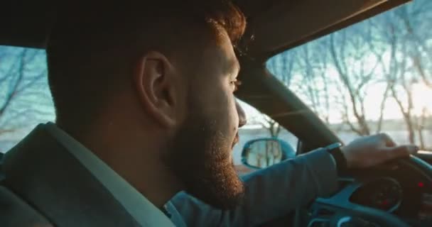 Zijaanzicht van het gezicht van de blanke glimlachte en vrolijke man bestuurder met een baard rijden een auto op een mooie late herfstdag. — Stockvideo