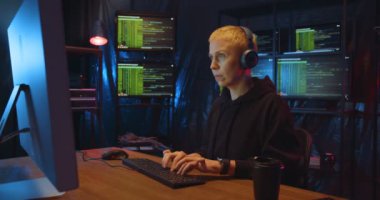 Kafkas kadın hacker, kulaklıklı, sarışın, siyah saçlı, masada monitörlü ve klavyeli bilgisayar başında oturuyor. Kadın hackleme çevrimiçi sistemi. Bilgi çalma kavramı.