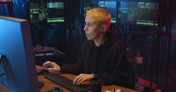 Blond medelålders vit kvinna som arbetar på natten vid datorn och skriver på tangentbordet på cyberpolisens kontor på natten. Kriminella hacka företagssystem och stjäla data från servrar. — Stockvideo