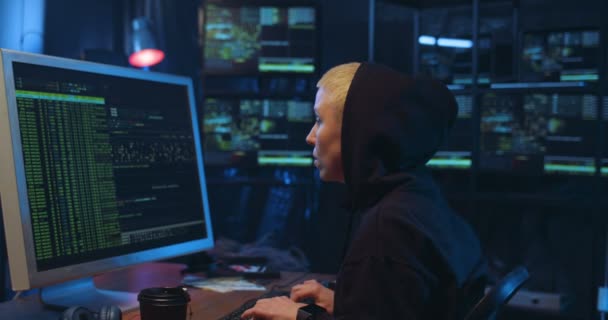 大きな画面の前でコンピュータ上で作業し、暗室でキーボードを入力し、女性の白人のサイバー警察官に戻ると側のビュー。ウイルス対策をしてる。インターネットデータセキュリティの概念. — ストック動画