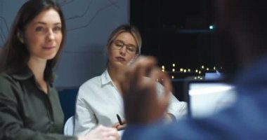 Beyaz tenli iki güzel kadın, ofiste patronlarını dinlerken, erkek omzunun arkasına bakıyorlar. Erkek, kadın şirket çalışanlarına bir şeyler anlatıyor. Arka..