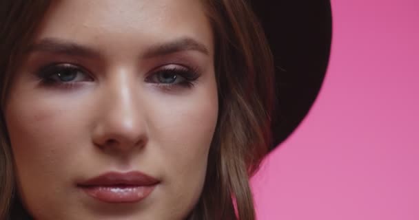 Model met gladde gezonde huid en naakte make-up kijkend naar de camera. Vrolijk stijlvol brunette meisje in hoed op zoek in de camera in de studio met roze achtergrond. vrouw op zoek naar camera in close-up. — Stockvideo