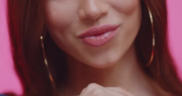 Обрезание лица красивой молодой женщины с чувствительными губами крупным планом на розовом фоне. Портрет брюнетки с длинными волосами и чувственными губами. Красивая девушка в студии . — стоковое видео