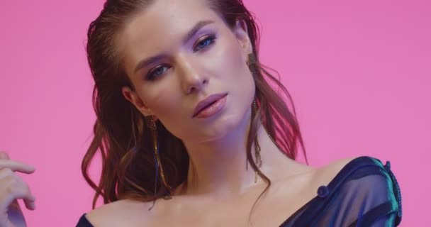 Hermosa modelo posando en un estudio rosa. Hermosa mujer con maquillaje increíble, peinado elegante y pendientes con clase en el fondo rosa . — Vídeos de Stock