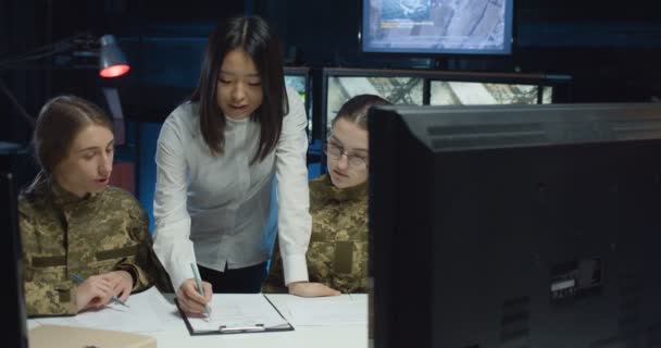 Due giovani ragazze caucasiche in uniforme di soldati che studiano nell'ufficio di controllo militare. asiatico femmina insegnante insegnamento donne di esercito per essere dispatchers in monitoraggio stanza . — Video Stock