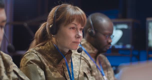 Multietniska manliga och kvinnliga militära avsändare i kamouflage uniformer och headset som arbetar på övervakningscentrum vid datorer. Kaukasiska och afroamerikanska män och kvinnor på arméns kontor. — Stockvideo