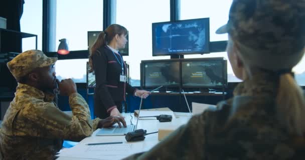 Жінка на зборах військового моніторингу стоїть за столом з багатонаціональними бойовиками чоловічої та жіночої статі та демонструє карти з дислокацією військ. Презентація концепції армії . — стокове відео